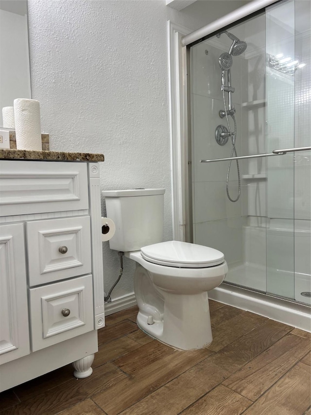 6904 Glenwood Dr, North Richland Hills, TX 76182 - full bath featuring a textured wall, wood finished floors, toilet, a stall shower, and vanity