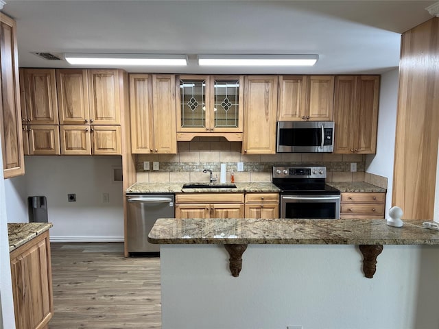6904 Glenwood Dr, North Richland Hills, TX 76182 - kitchen featuring appliances with stainless steel finishes, a sink, a kitchen bar, and light wood-style floors