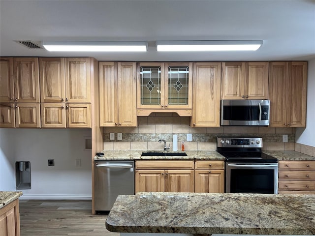 6904 Glenwood Dr, North Richland Hills, TX 76182 - kitchen with appliances with stainless steel finishes, a sink, tasteful backsplash, light stone counters, and wood finished floors