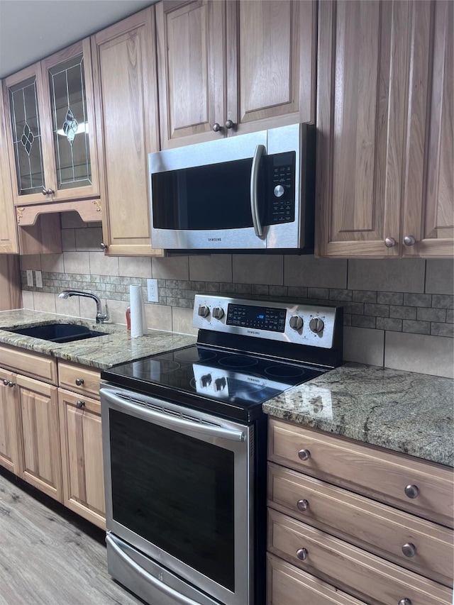 6904 Glenwood Dr, North Richland Hills, TX 76182 - kitchen with stainless steel appliances, a sink, decorative backsplash, and light stone counters