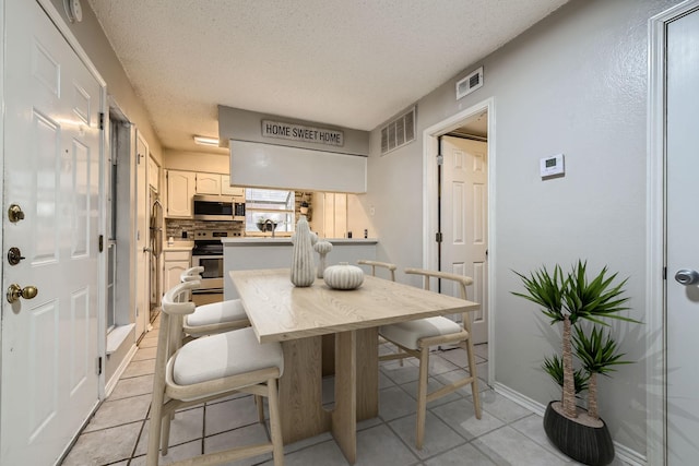 dining space featuring light tile patterned floors, a textured ceiling, and visible vents