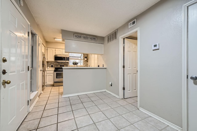 kitchen featuring appliances with stainless steel finishes, light tile patterned floors, visible vents, and a textured ceiling