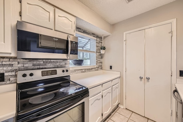 kitchen featuring appliances with stainless steel finishes, light countertops, white cabinetry, a textured ceiling, and light tile patterned flooring