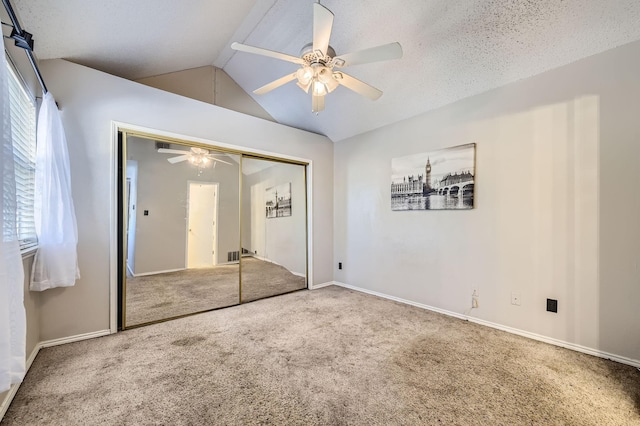 unfurnished bedroom with a closet, a ceiling fan, carpet, baseboards, and lofted ceiling