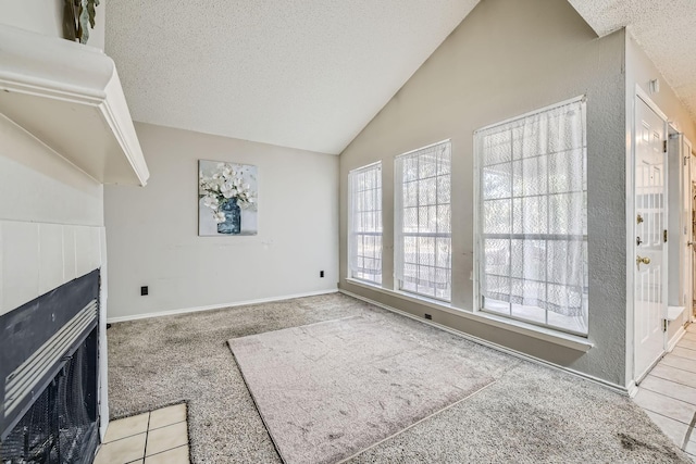 unfurnished living room featuring a textured ceiling, carpet flooring, a fireplace with flush hearth, and vaulted ceiling