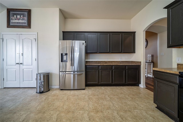 kitchen featuring baseboards, arched walkways, and stainless steel fridge with ice dispenser