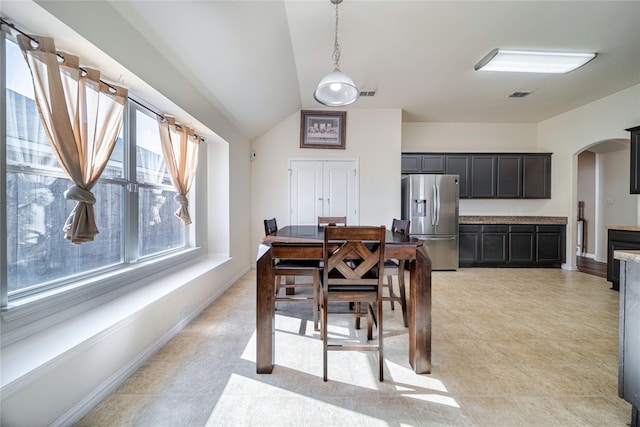 dining room featuring visible vents, arched walkways, baseboards, and vaulted ceiling