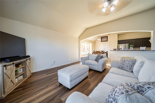 living room featuring dark wood-type flooring, arched walkways, baseboards, ceiling fan, and vaulted ceiling