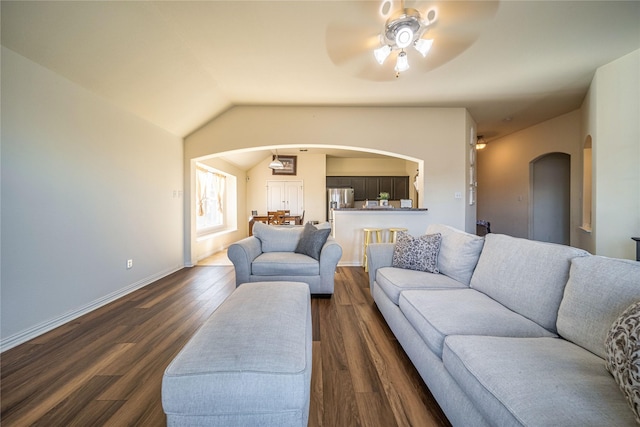 living room with dark wood-style floors, a ceiling fan, baseboards, arched walkways, and vaulted ceiling