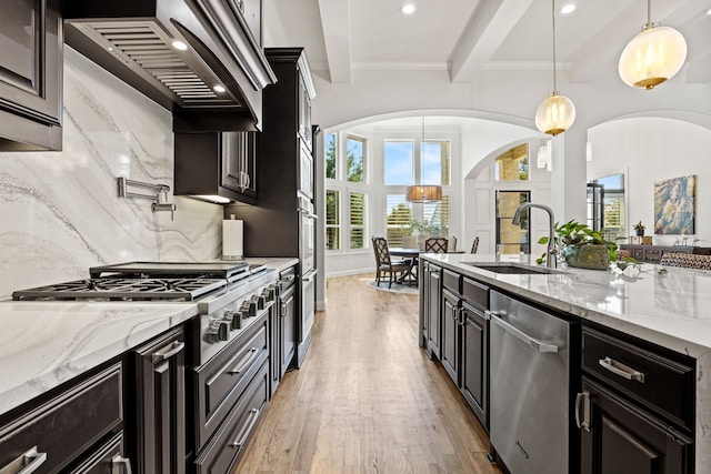 504 Shadow Wood Ln, Heath, TX 75032 - kitchen featuring appliances with stainless steel finishes, arched walkways, a sink, light wood finished floors, and healthy amount of natural light