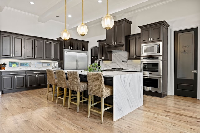 504 Shadow Wood Ln, Heath, TX 75032 - kitchen with built in appliances, crown molding, decorative backsplash, a kitchen island with sink, and light wood-type flooring