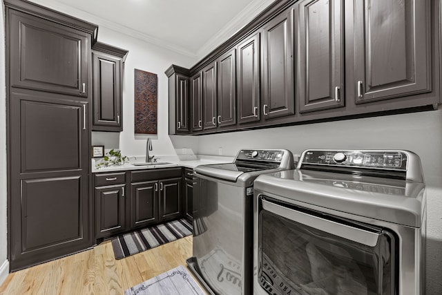 504 Shadow Wood Ln, Heath, TX 75032 - laundry room with washing machine and clothes dryer, cabinet space, ornamental molding, and light wood-style floors