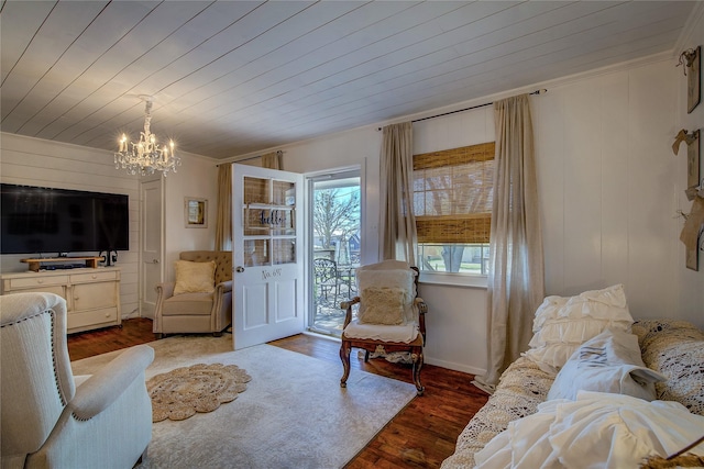 living room with crown molding, wood finished floors, wood ceiling, and a chandelier