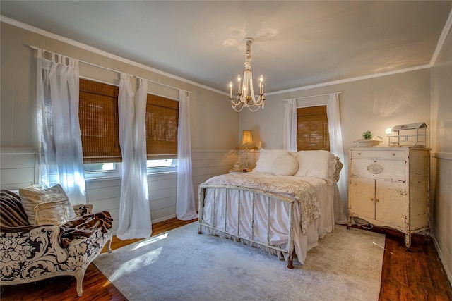 bedroom featuring wood finished floors, ornamental molding, and a chandelier