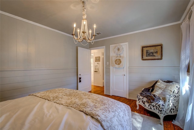 bedroom with visible vents, ornamental molding, wood finished floors, and an inviting chandelier