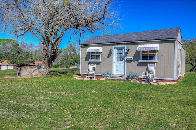 view of front of home with a front yard and a shingled roof