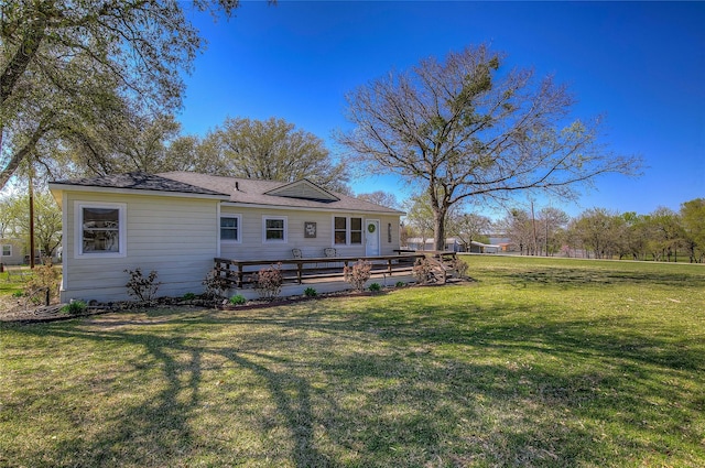 rear view of property featuring a wooden deck and a lawn