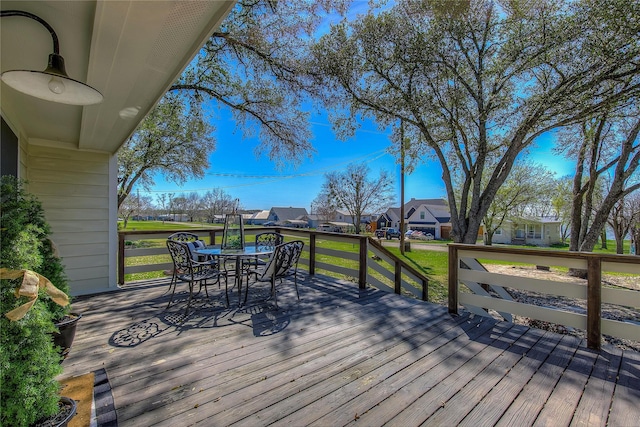 deck with a residential view, a lawn, and outdoor dining space