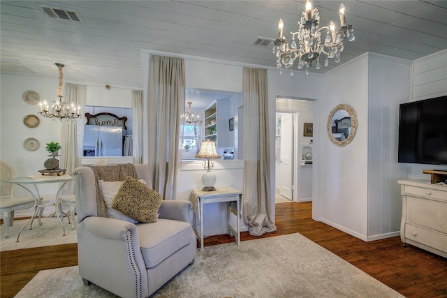 sitting room featuring wood finished floors, ornamental molding, a chandelier, and visible vents