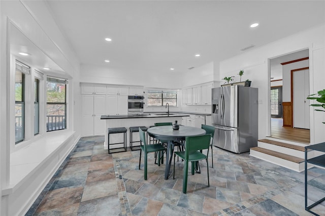 kitchen with a sink, white cabinets, stone finish floor, and stainless steel appliances