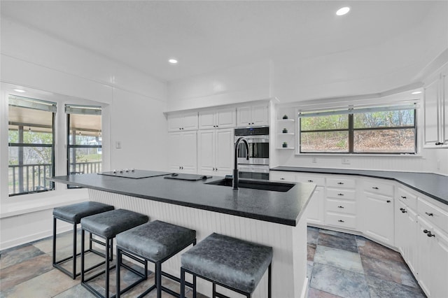 kitchen featuring dark countertops, stone finish floor, plenty of natural light, and stainless steel double oven