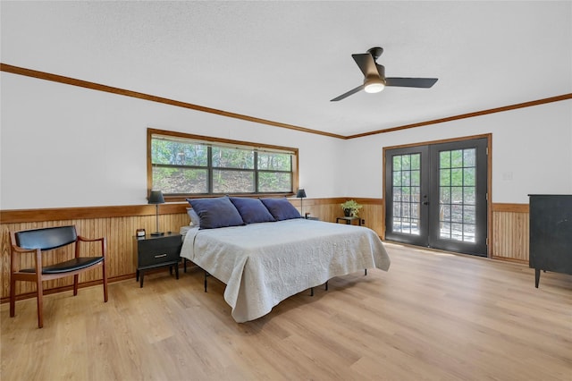 bedroom with wainscoting, french doors, light wood-style flooring, and multiple windows