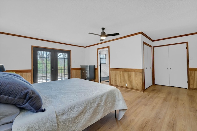 bedroom featuring access to outside, french doors, a wainscoted wall, and light wood finished floors