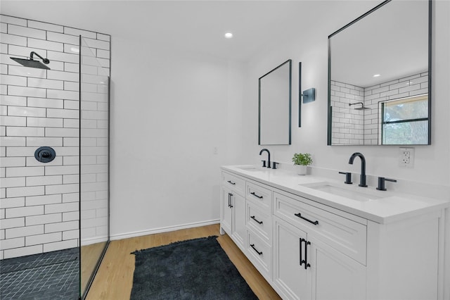 bathroom with double vanity, wood finished floors, walk in shower, and a sink