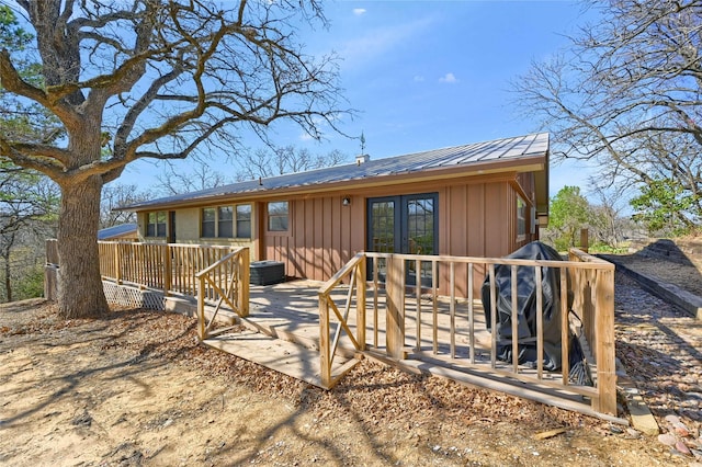 rear view of house with a deck, french doors, board and batten siding, and metal roof