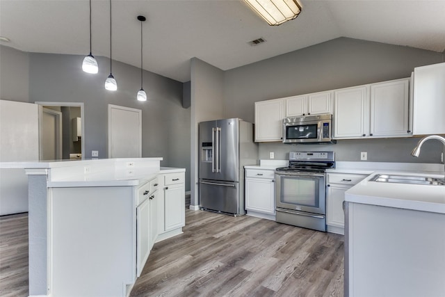 kitchen with appliances with stainless steel finishes, a sink, a center island, light countertops, and light wood-style floors