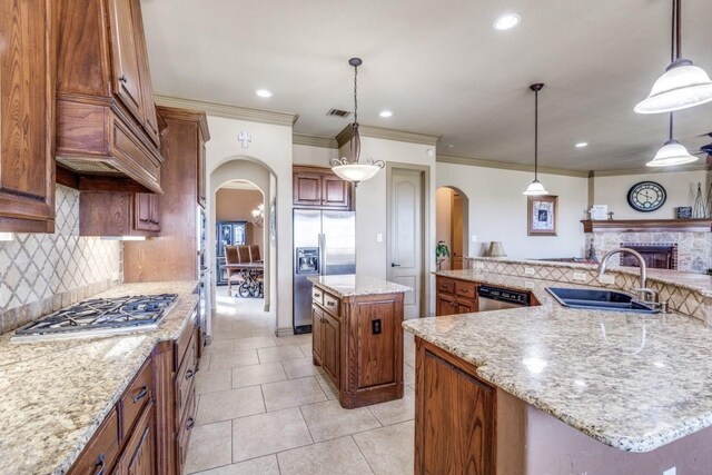 1211 Meredith Creek Ln, Fort Worth, TX 76179 - kitchen with brown cabinets, appliances with stainless steel finishes, arched walkways, a sink, and a large island