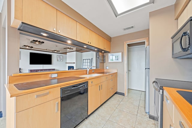 kitchen featuring visible vents, light tile patterned flooring, a sink, light brown cabinetry, and black appliances