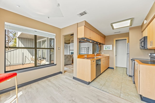 kitchen featuring visible vents, light brown cabinets, and black appliances