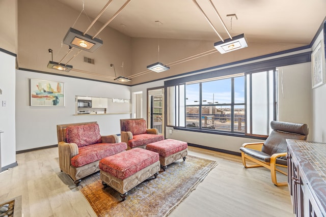 living area with visible vents, lofted ceiling, baseboards, and light wood-style flooring