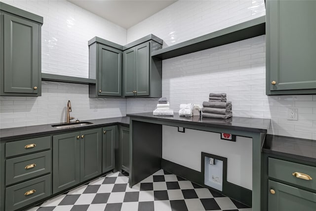 kitchen featuring dark countertops, green cabinetry, tile patterned floors, and a sink