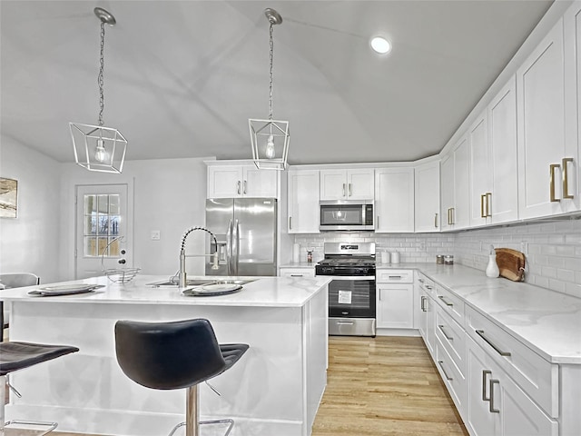 kitchen with a sink, white cabinetry, a breakfast bar area, appliances with stainless steel finishes, and light wood-style flooring