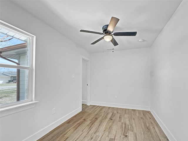spare room featuring baseboards, visible vents, light wood-style flooring, and a ceiling fan