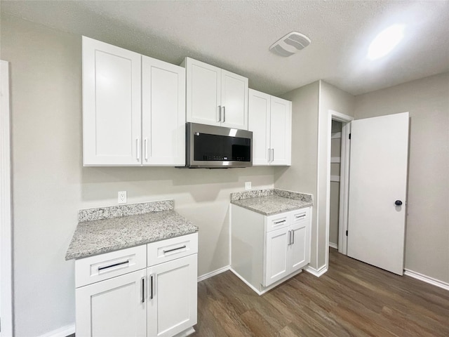 1505 W Collin, Corsicana, TX 75110 - kitchen featuring stainless steel microwave, dark wood-type flooring, baseboards, white cabinetry, and a textured ceiling