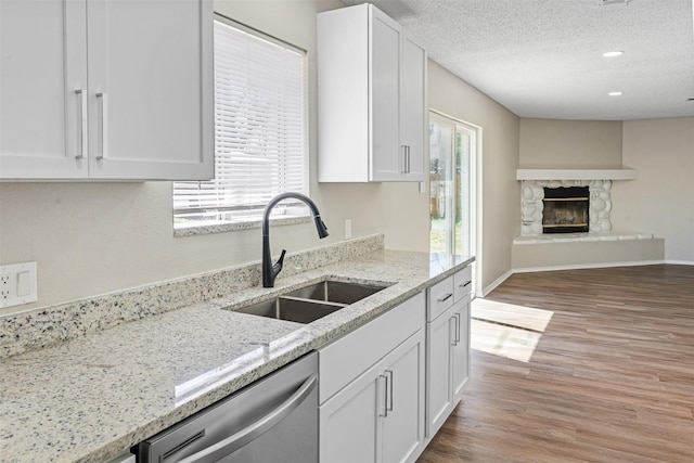 1505 W Collin, Corsicana, TX 75110 - kitchen with a sink, dishwasher, white cabinets, light wood-style flooring, and a stone fireplace