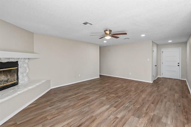 1505 W Collin, Corsicana, TX 75110 - unfurnished living room featuring ceiling fan, wood finished floors, a stone fireplace, recessed lighting, and a textured ceiling