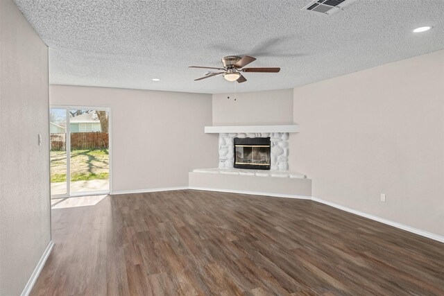 1505 W Collin, Corsicana, TX 75110 - unfurnished living room with ceiling fan, wood finished floors, a stone fireplace, baseboards, and a textured ceiling