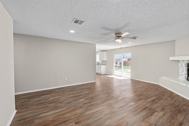 1505 W Collin, Corsicana, TX 75110 - unfurnished living room with ceiling fan, wood finished floors, a fireplace, baseboards, and a textured ceiling