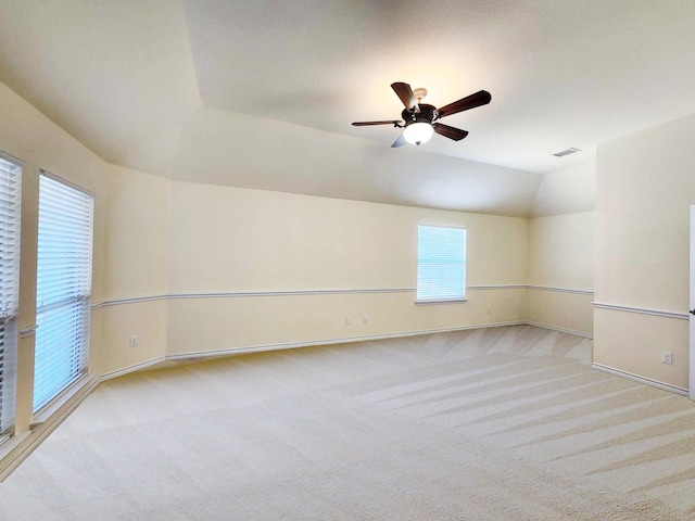 carpeted empty room with vaulted ceiling, baseboards, and a ceiling fan