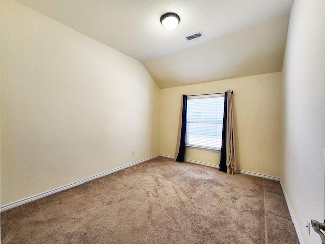spare room with vaulted ceiling, visible vents, carpet flooring, and baseboards