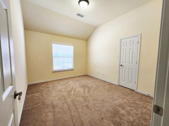 unfurnished room with vaulted ceiling, carpet flooring, visible vents, and baseboards