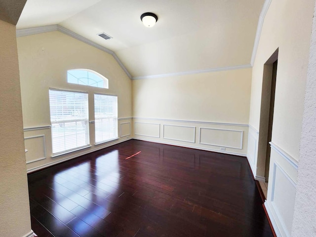 unfurnished room with crown molding, wainscoting, hardwood / wood-style flooring, lofted ceiling, and visible vents