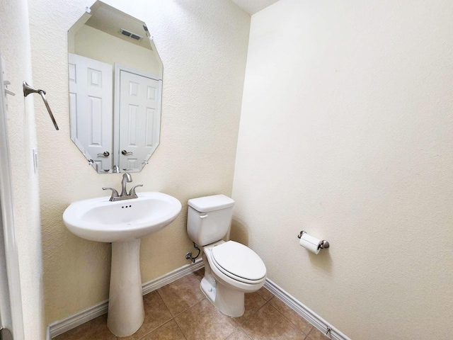 bathroom featuring toilet, tile patterned flooring, and baseboards