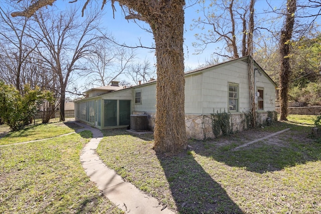 rear view of house featuring a sunroom, central air condition unit, fence, and a lawn