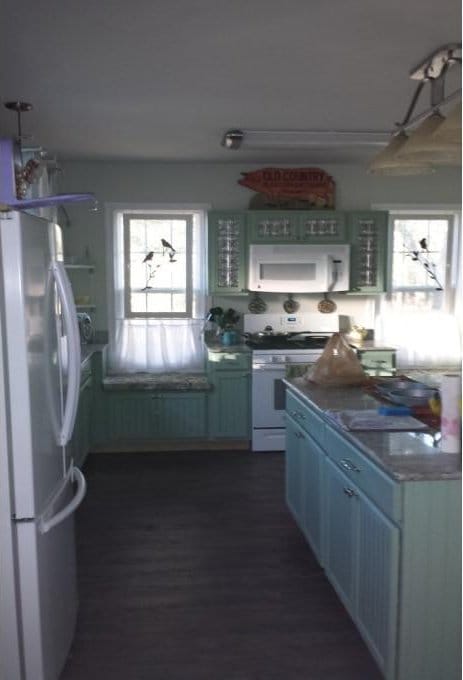 kitchen with dark wood finished floors, white appliances, and dark countertops