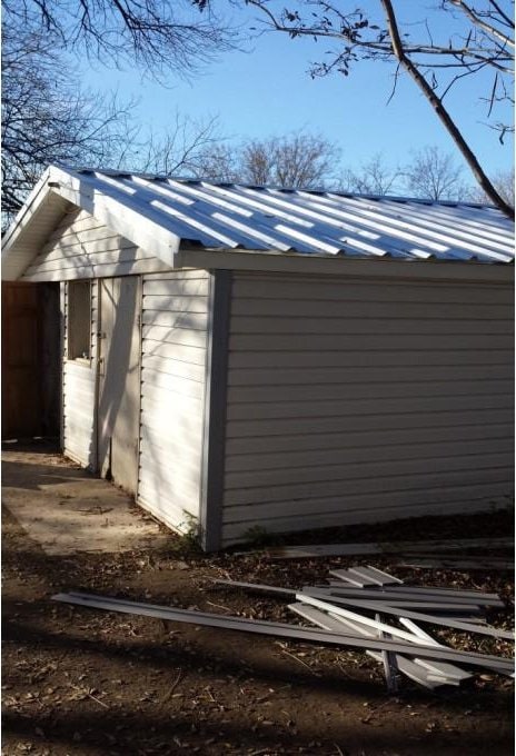 view of side of property with a standing seam roof, metal roof, a storage shed, and an outdoor structure